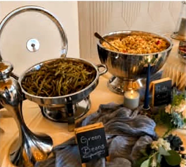 Polished chafing dishes of green beans and seasoned rice, labelled with a small chalkboard sign.